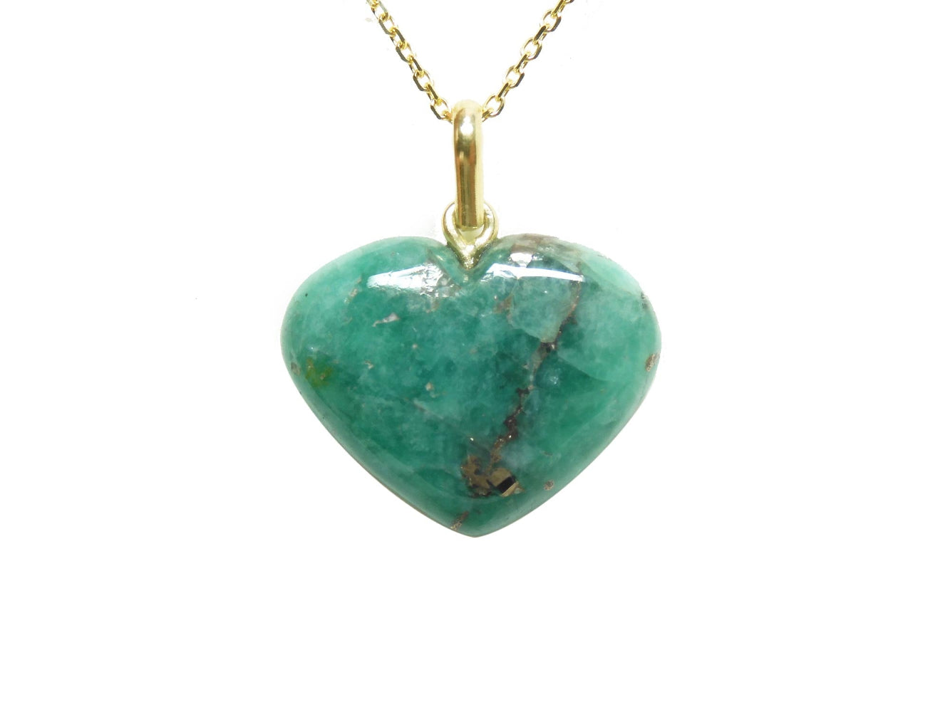 Heart-shaped hand carved emerald cabochon stone pendant on a gold chain on a topside view.