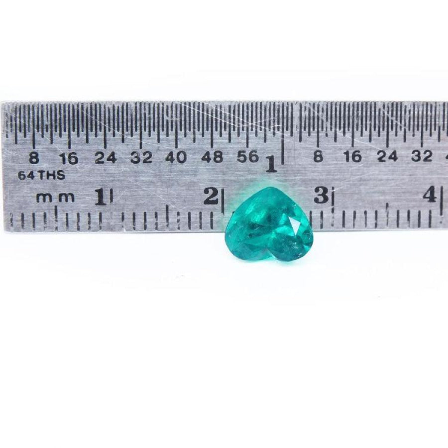 1.26 ct. heart cut Colombian emerald with vibrant bluish-green color, shown next to a ruler for scale.