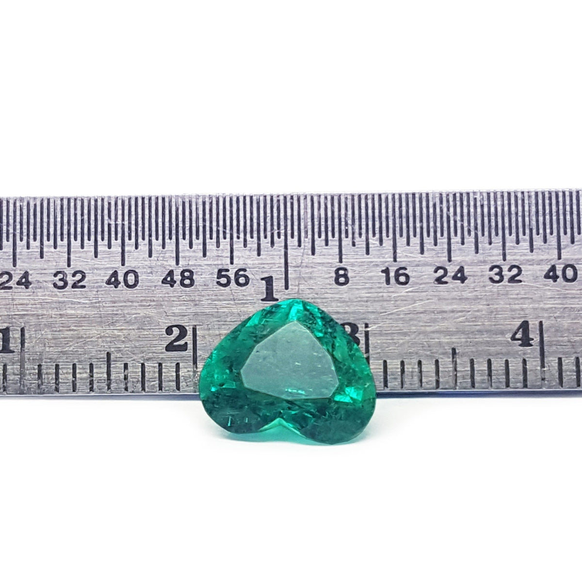 GIA certified heart cut natural colombian emerald, front inverted position next to a rule for measuring size