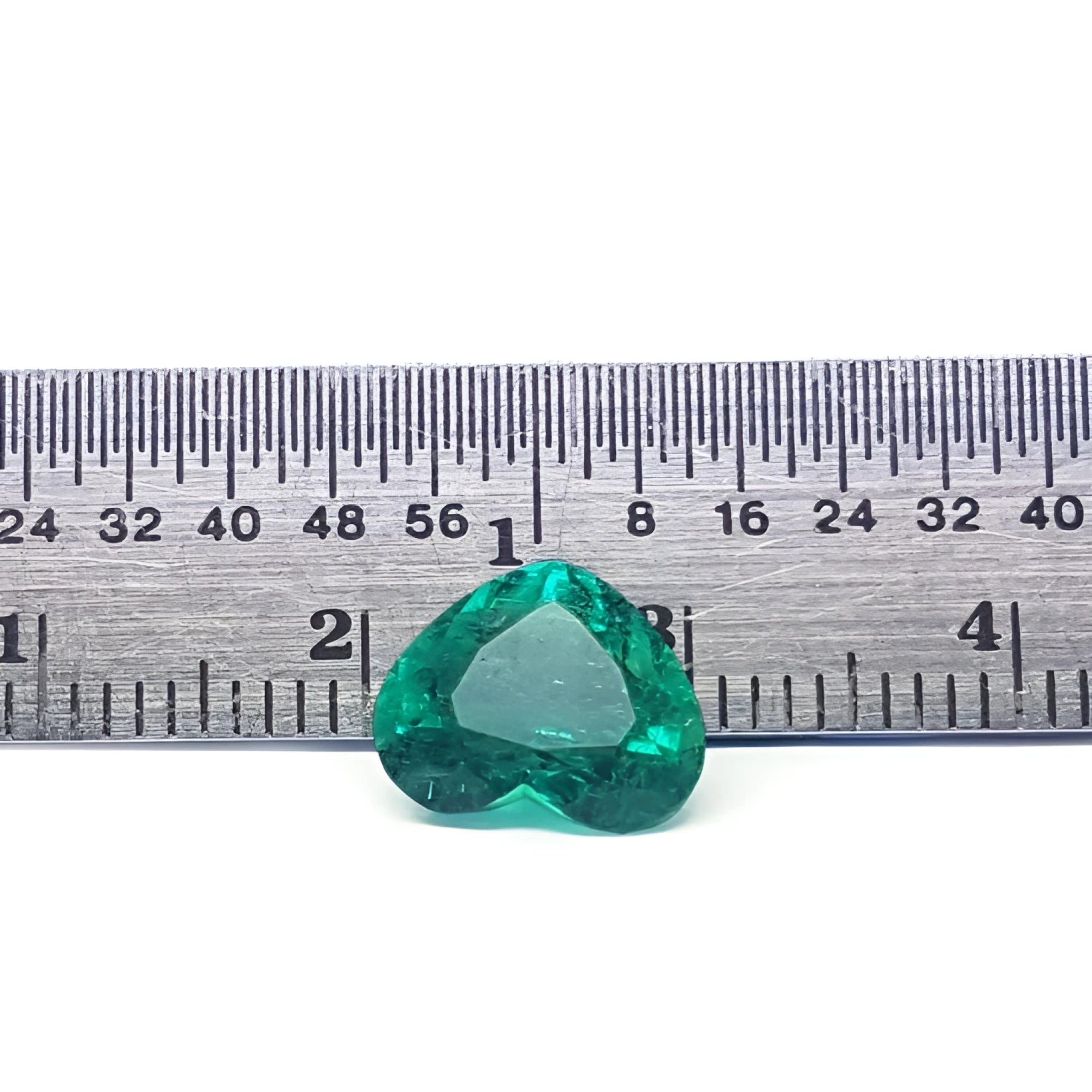 GIA certified 2.54 ct heart-cut natural Colombian emerald, sparkling bluish-green, on a ruler.