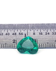 GIA certified heart cut natural colombian emerald, front inverted position next to a rule for measuring size