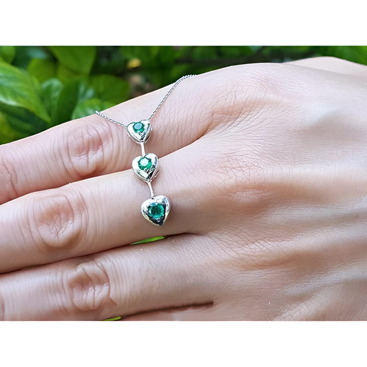 14K white gold heart journey pendant necklace with three round-cut Colombian emeralds.