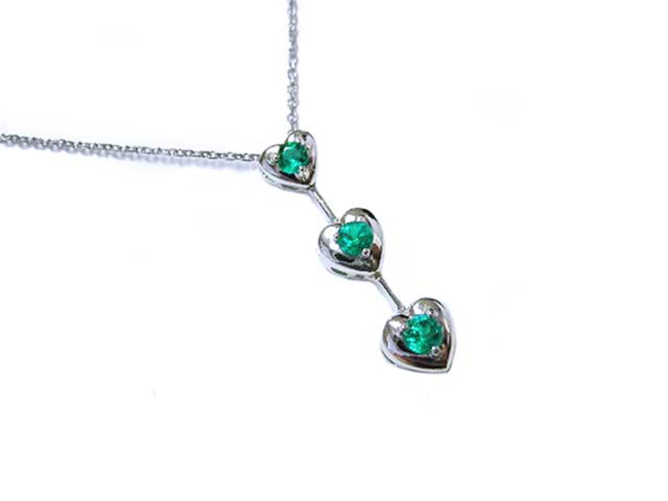 Three hearts emerald journey pendant necklace in 14k white gold topside view.