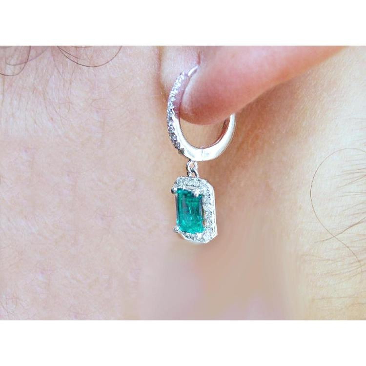 14k white gold hoop earrings with medium deep green emerald dangle, framed by natural diamonds.