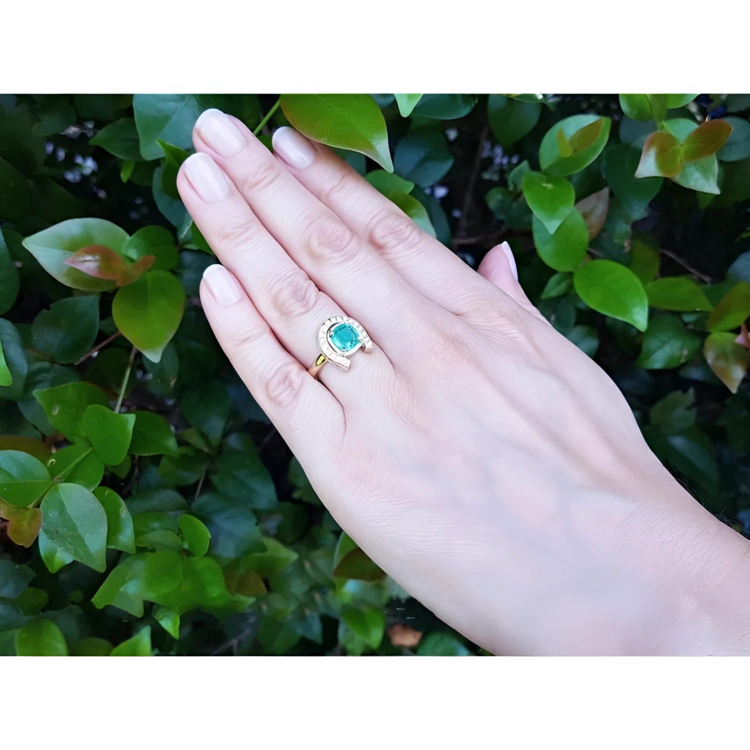 1.48 ct. cushion-cut Colombian emerald horseshoe ring in 14K yellow gold with diamonds on a hand.