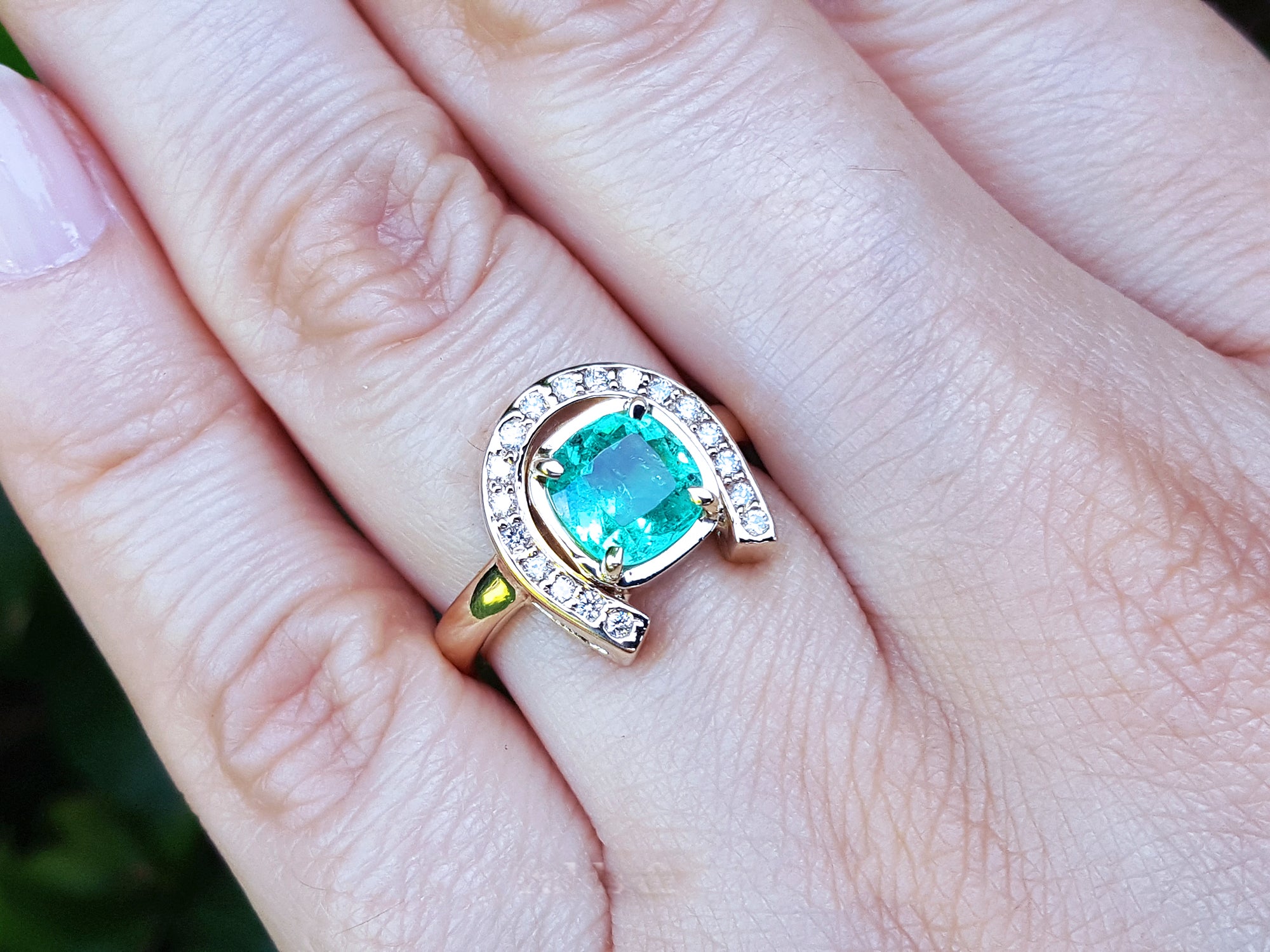 A closer view of a 1.48 ct. horseshoe emerald ring for women crafted in 14k yellow gold on a person&#39;s finger.