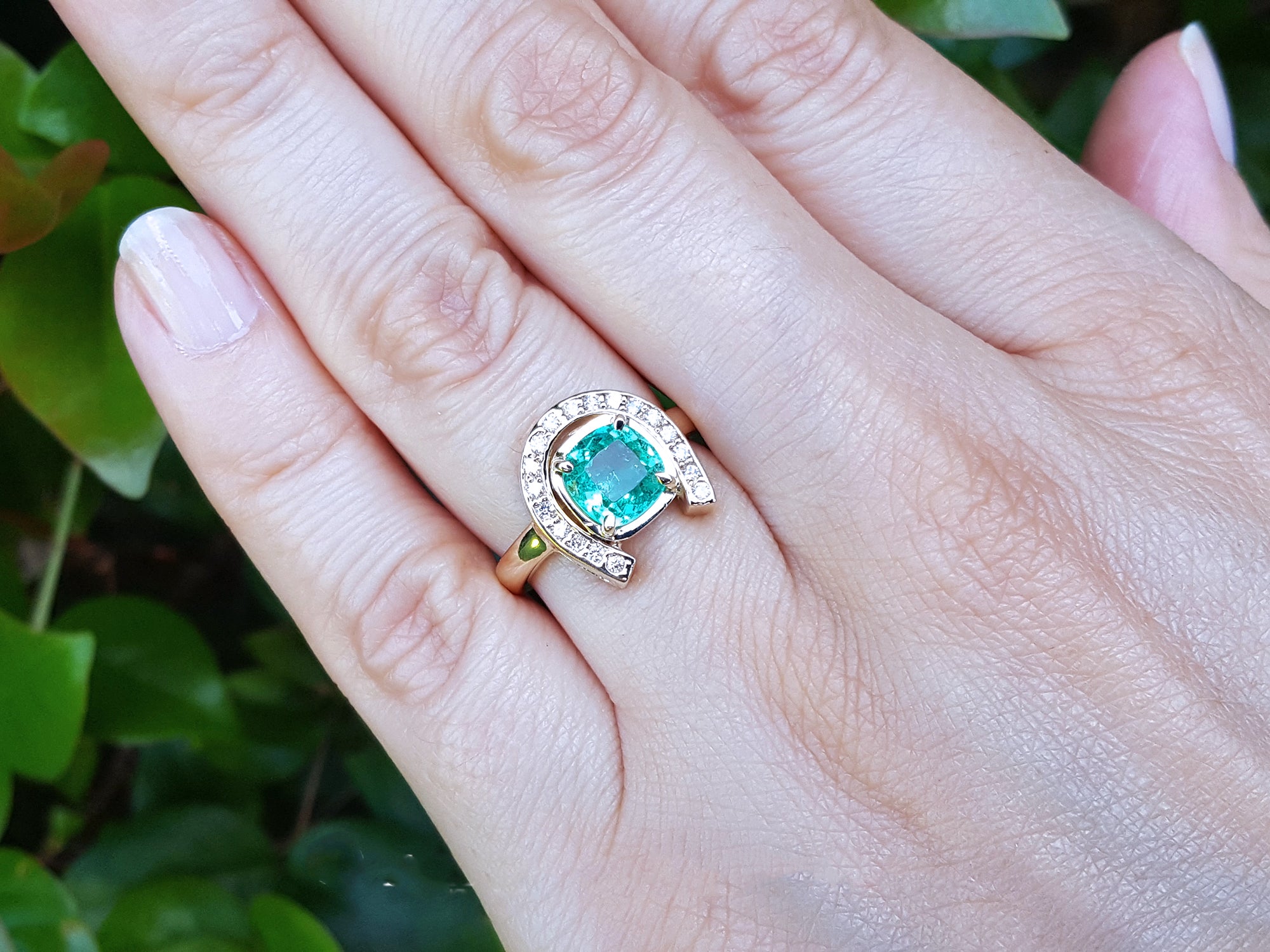A close up of a 1.48 ct. horseshoe emerald ring for women crafted in 14k yellow gold on a woman&#39;s hand