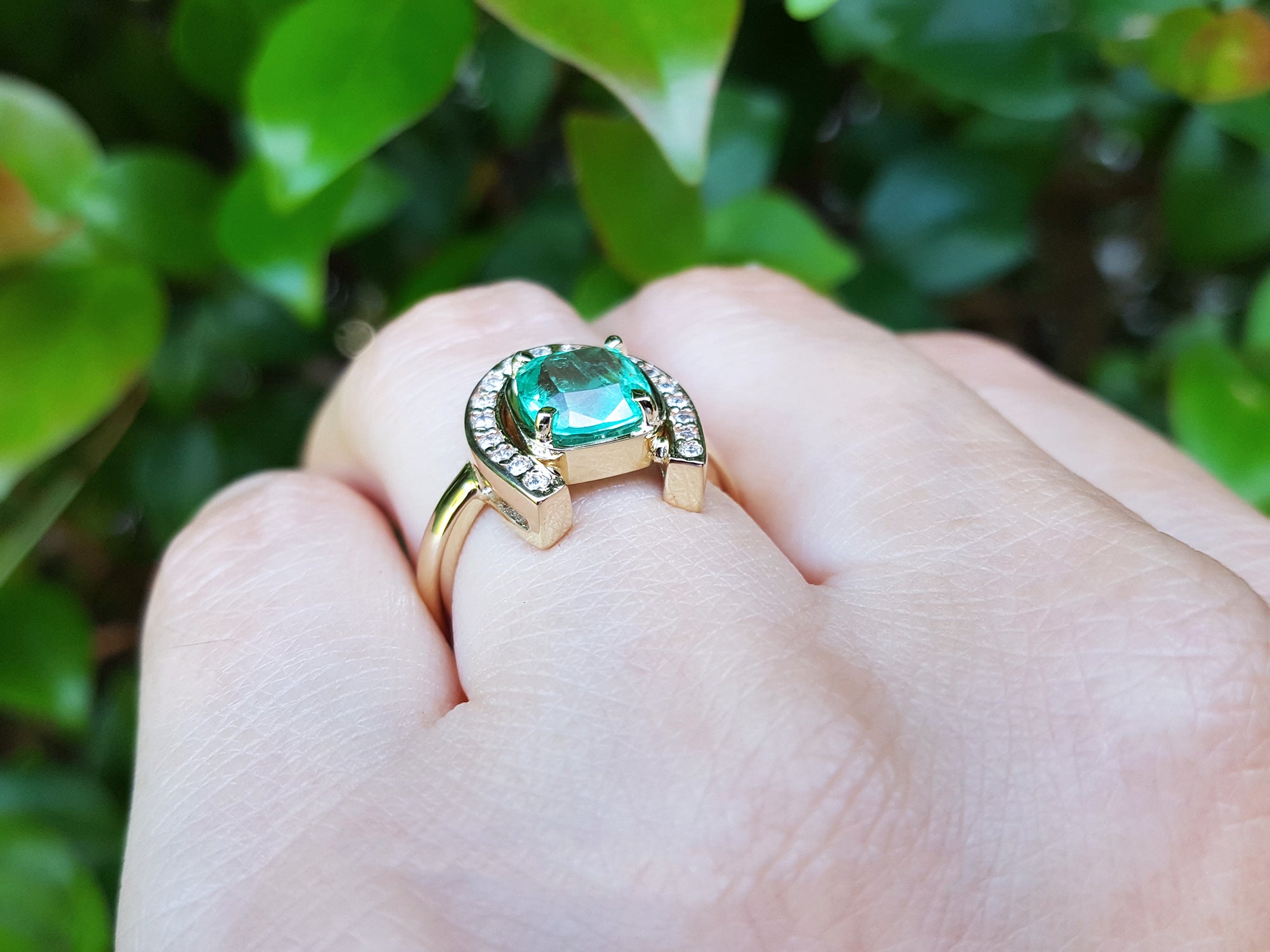 The underside view of a horseshoe emerald ring for women crafted in 14k yellow gold on a person&#39;s finger.