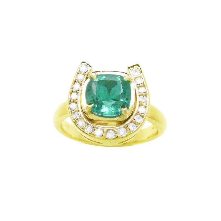 This horseshoe emerald ring displays a cushion-cut emerald framed by a semicircle of diamonds, in yellow gold.