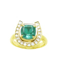 This horseshoe emerald ring displays a cushion-cut emerald framed by a semicircle of diamonds, in yellow gold.