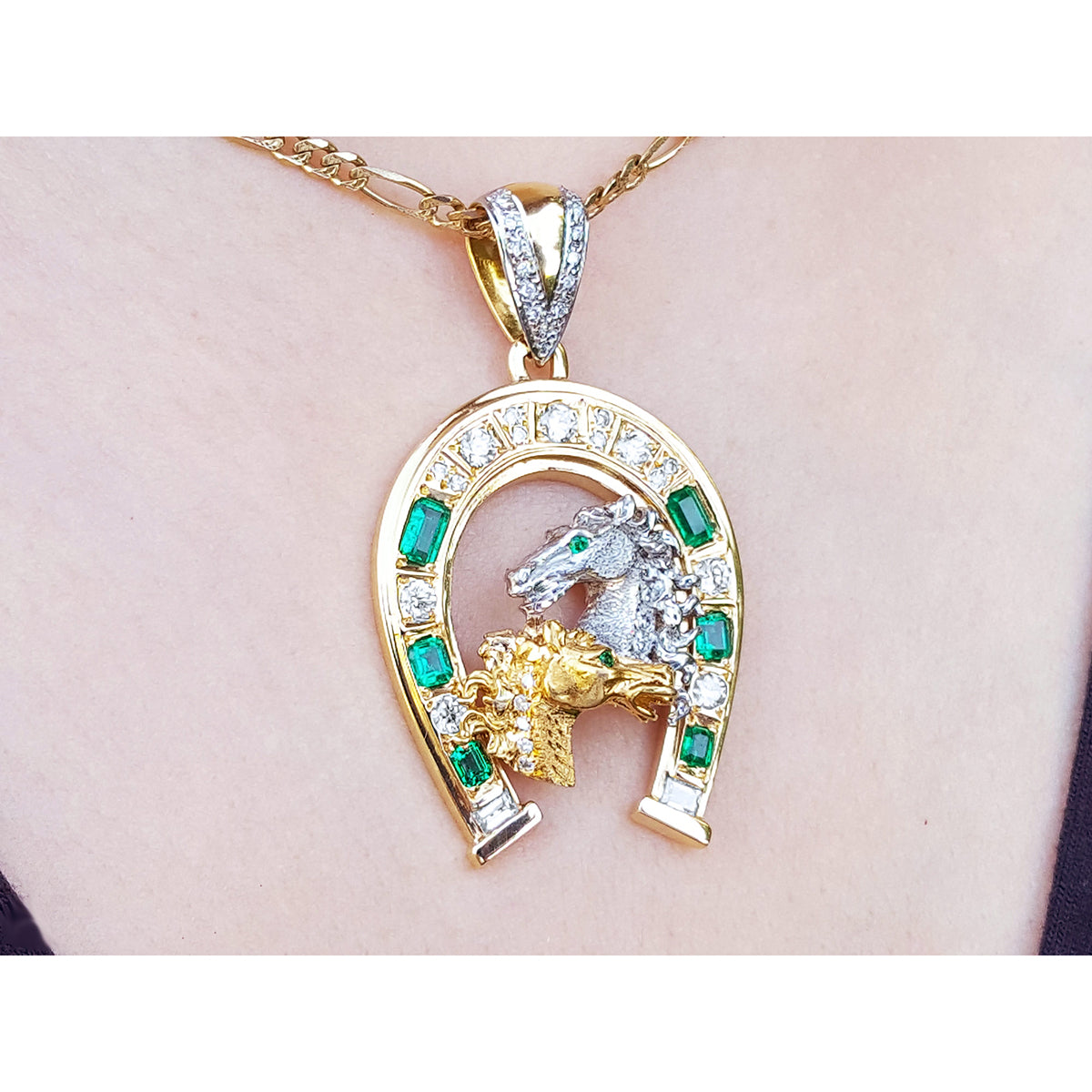 Gold pendant with horse&#39;s heads design on a pink skin background.