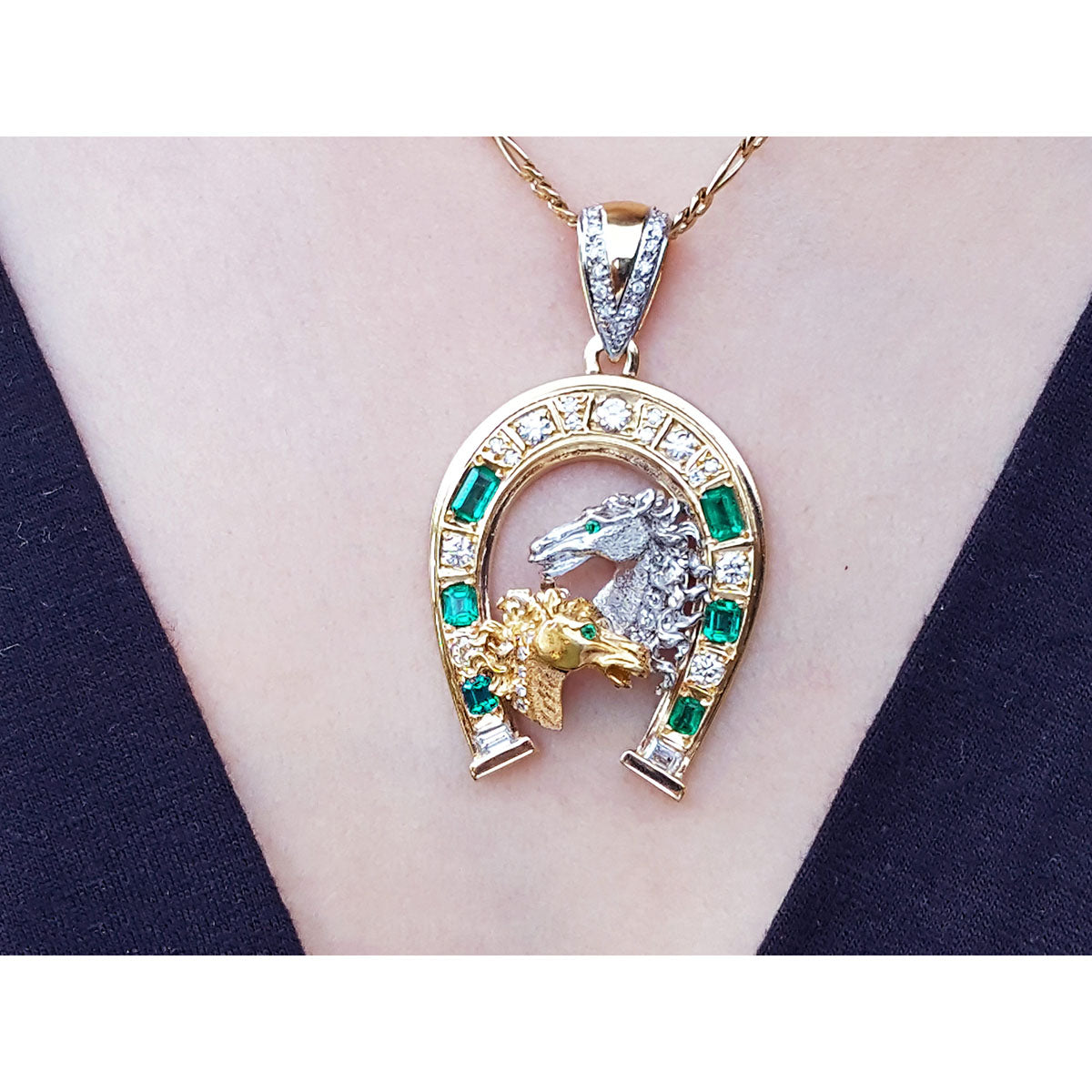 Yellow and white gold horse pendant with emerald stones on a gold chain on a person&#39;s neck.
