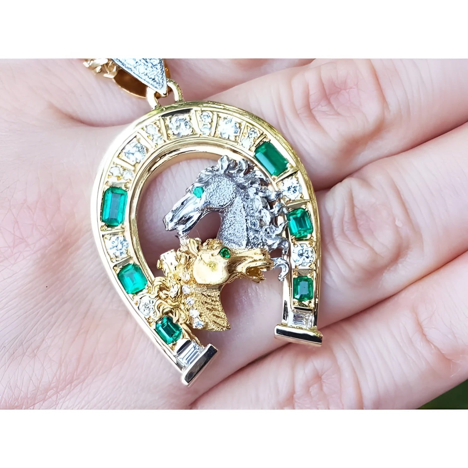 18K yellow gold horseshoe pendant with emeralds, diamonds, and two horse heads.