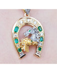 Gold horse pendant with natural emeralds and diamonds on a pink skin background