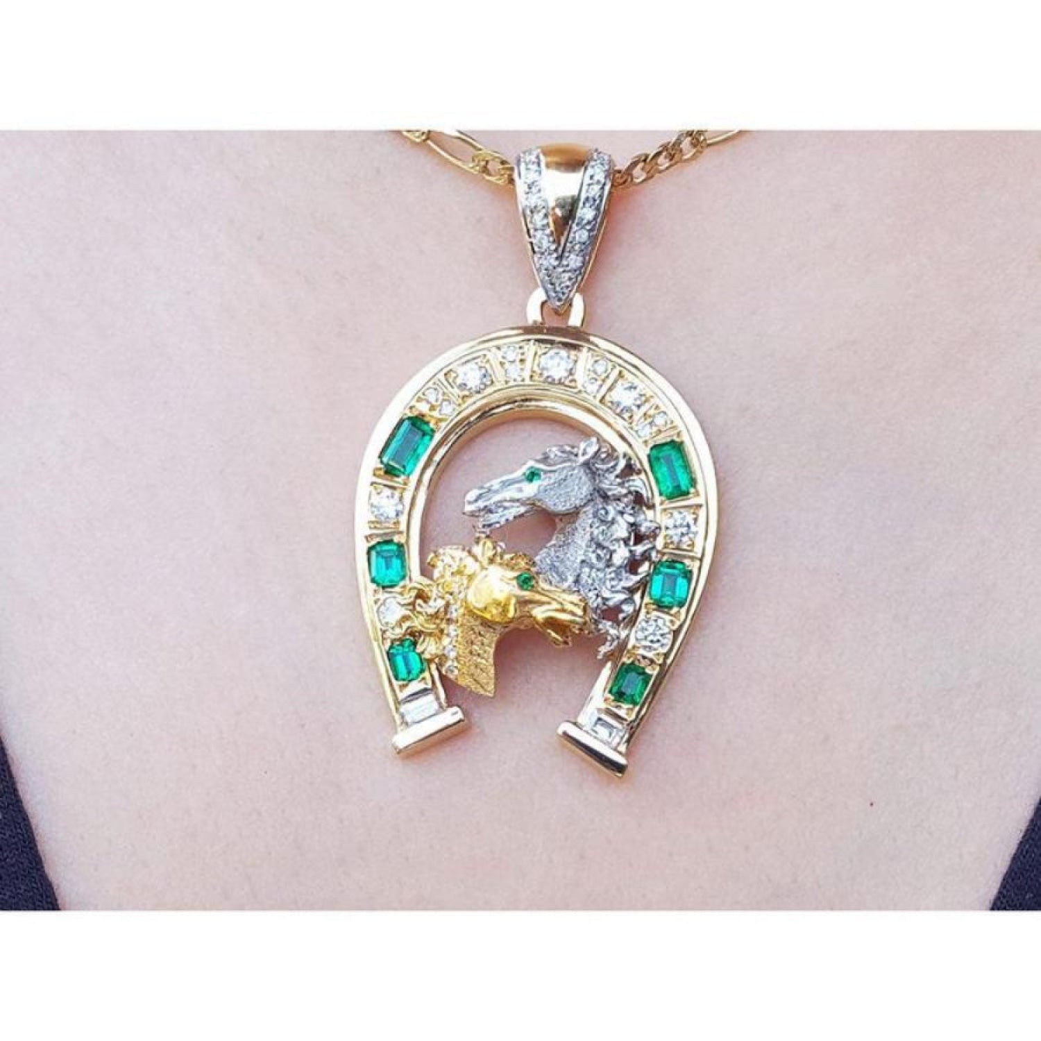 18K yellow gold horseshoe pendant with colombian emeralds, diamonds, and two horse heads.