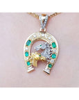 18K yellow gold horseshoe pendant with colombian emeralds, diamonds, and two horse heads.
