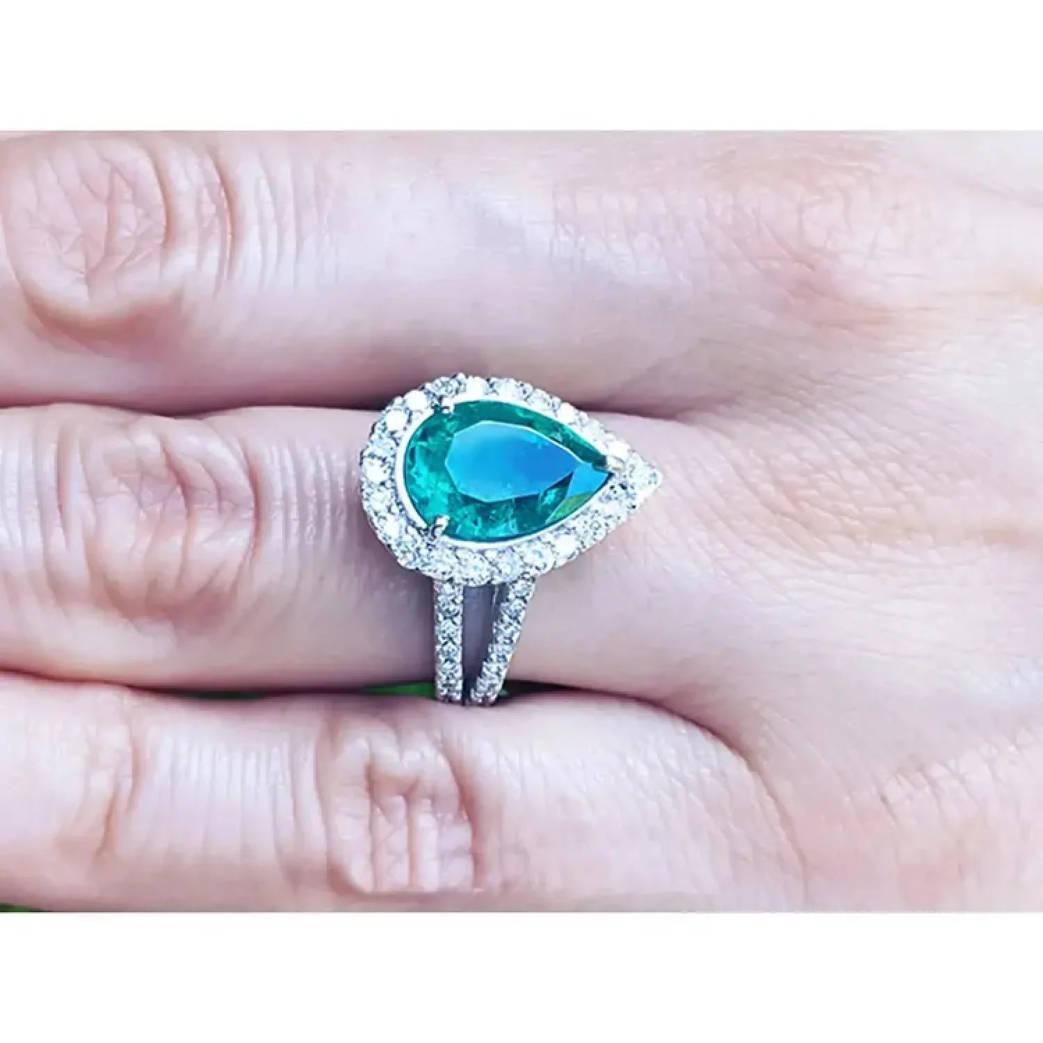 Anillo de compromiso de oro blanco con esmeralda pera de 4.02 ct rodeada de diamantes.