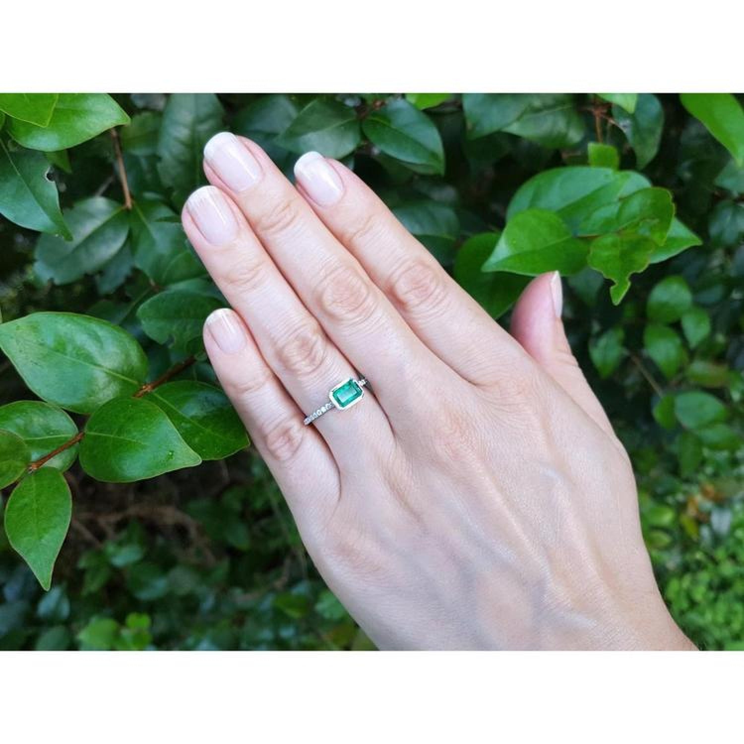 14K white gold ring with a bezel-set 0.73 ct emerald and accent diamonds on a hand.