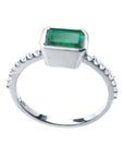 A detailed view of an emerald and accent diamonds ring, highlighting the top, side gallery, and band.