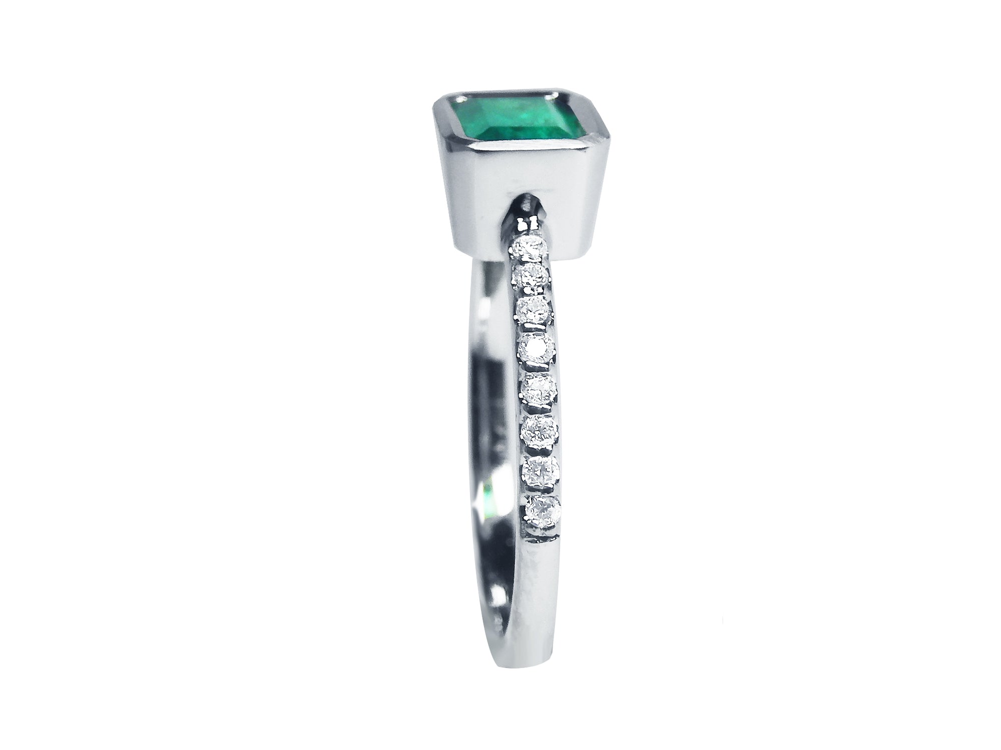 A detailed view of an emerald bezel set emerald ring, highlighting the top, side gallery, and band with diamonds studded.