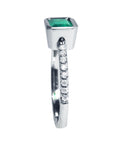 A detailed view of an emerald bezel set emerald ring, highlighting the top, side gallery, and band with diamonds studded.