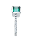 A bezel set emerald and diamond-studded band ring perspective.