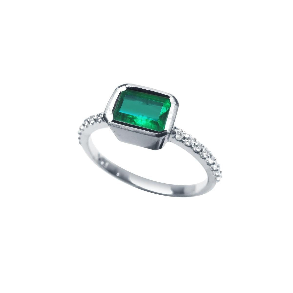 The tilted position of this bezel set emerald ring reveals the top setting, a portion of the gallery, and the band design.