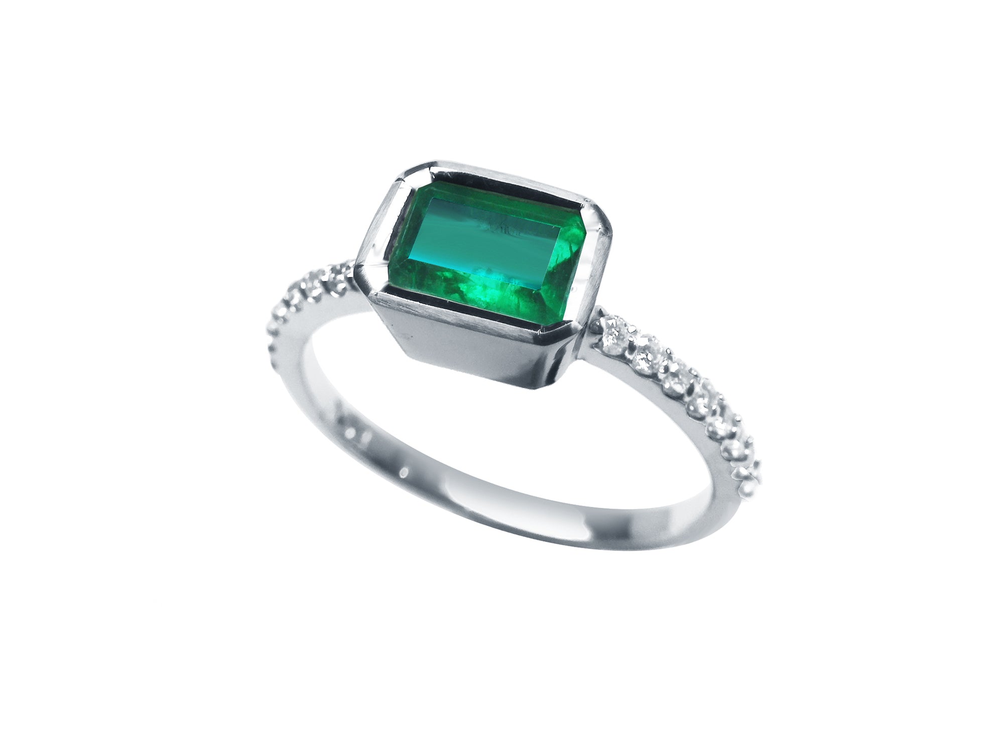 The tilted position of this bezel set emerald ring reveals the top setting, a portion of the gallery, and the band design.
