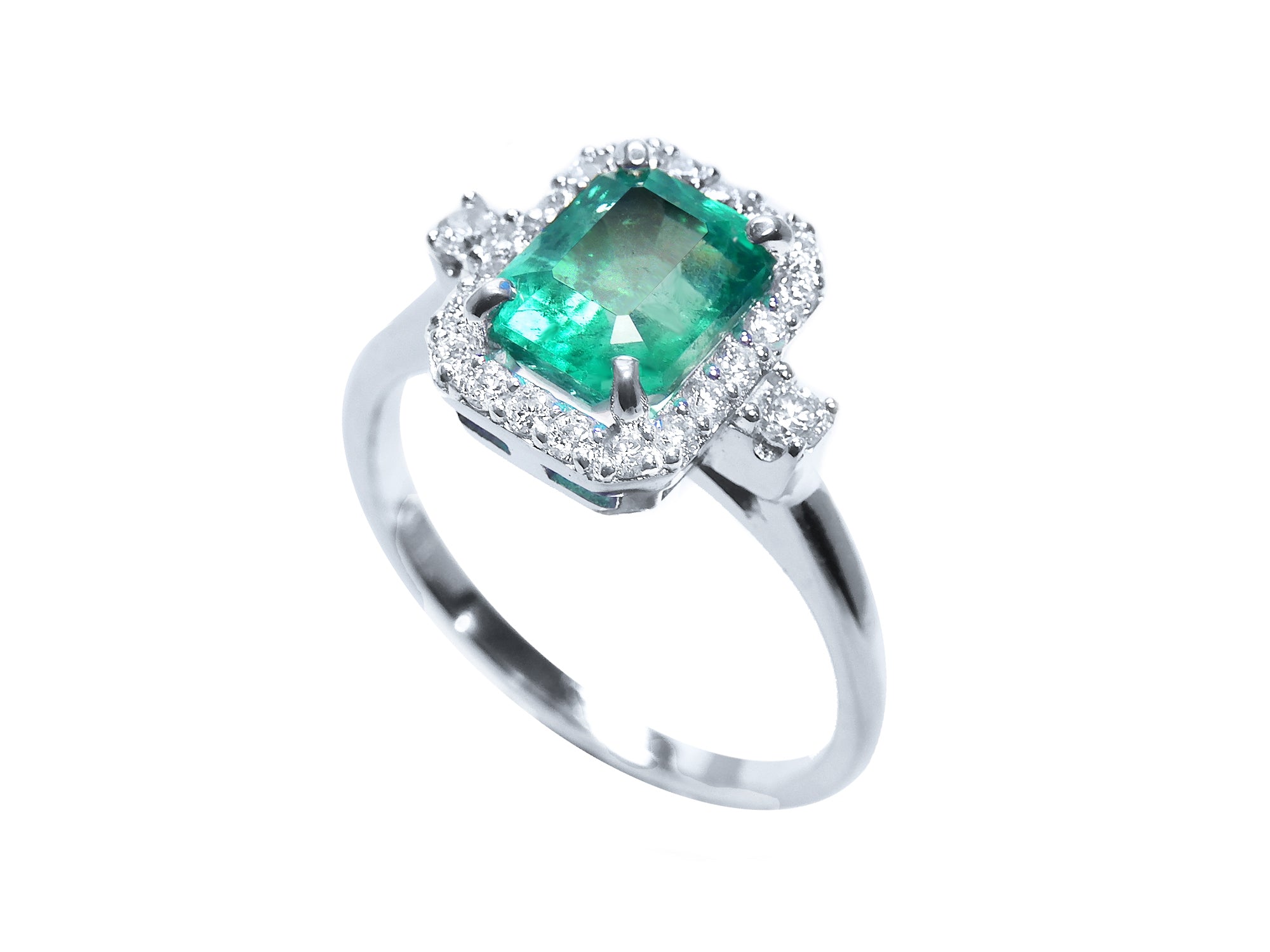 This affordable emerald engagement ring with a halo diamond in a tilted position shows the top ans side profile.