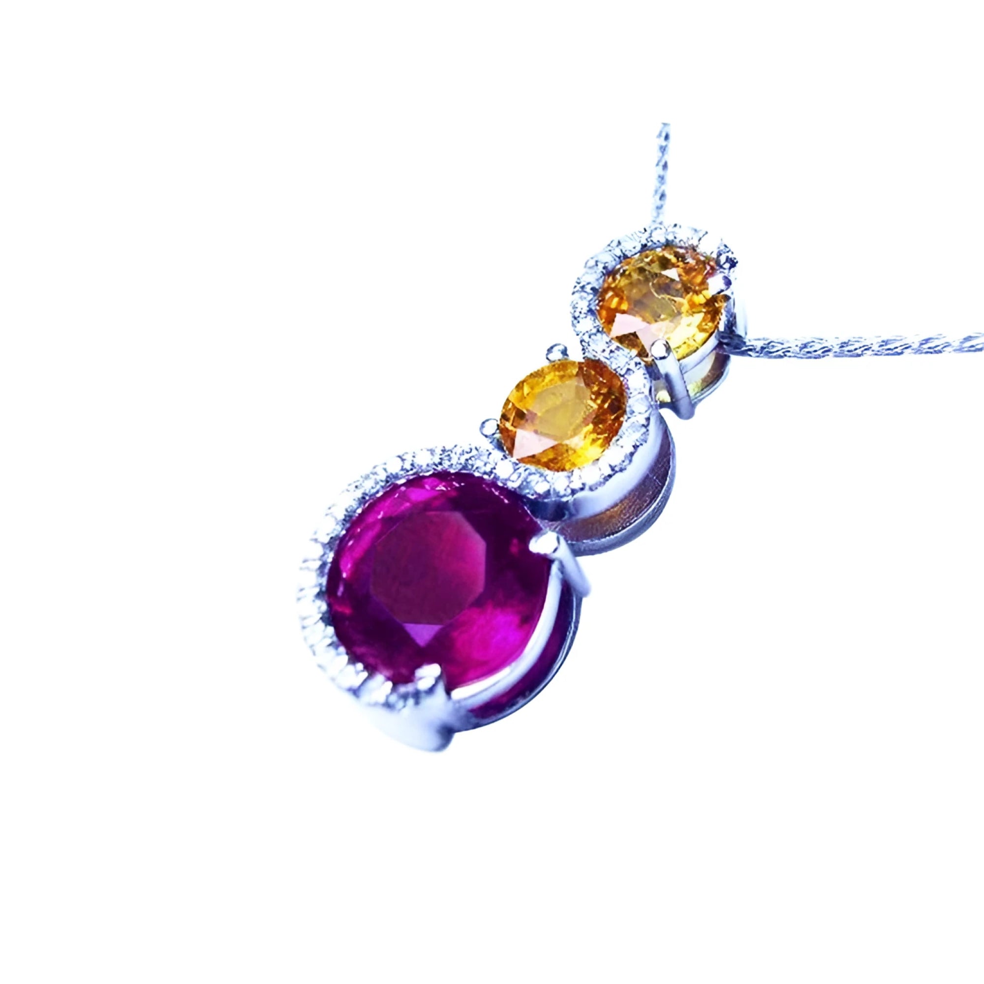 14K white gold journey pendant with a round ruby, two yellow sapphires, and diamond accents.