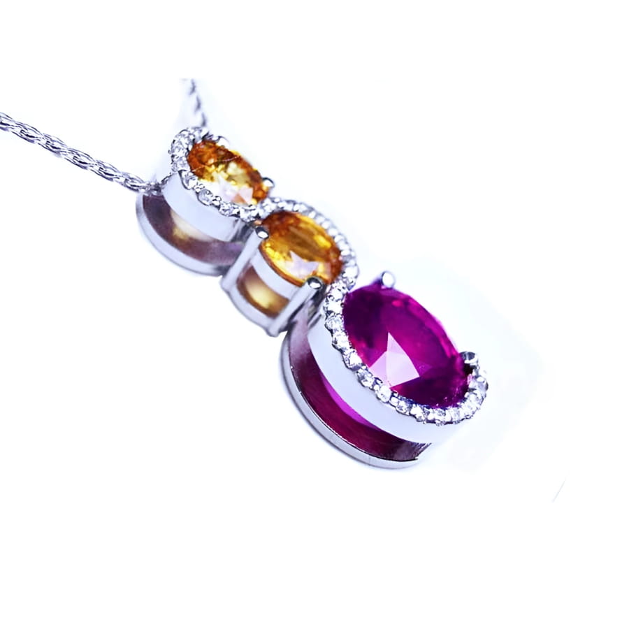 14K white gold ruby journey pendant with two yellow sapphires and diamond accents.