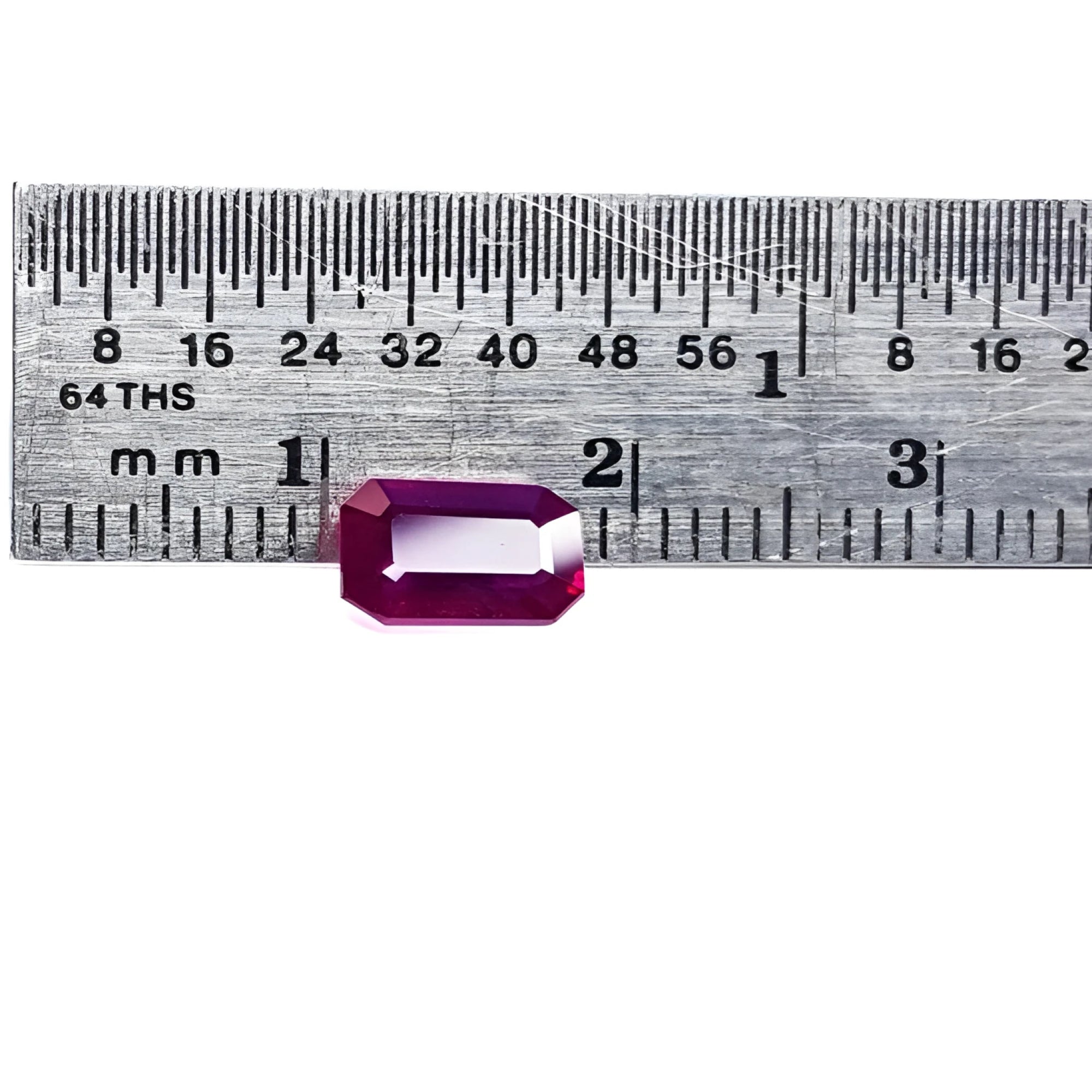 1.12 ct deep red emerald-cut natural ruby gemstone next to a ruler for scale.