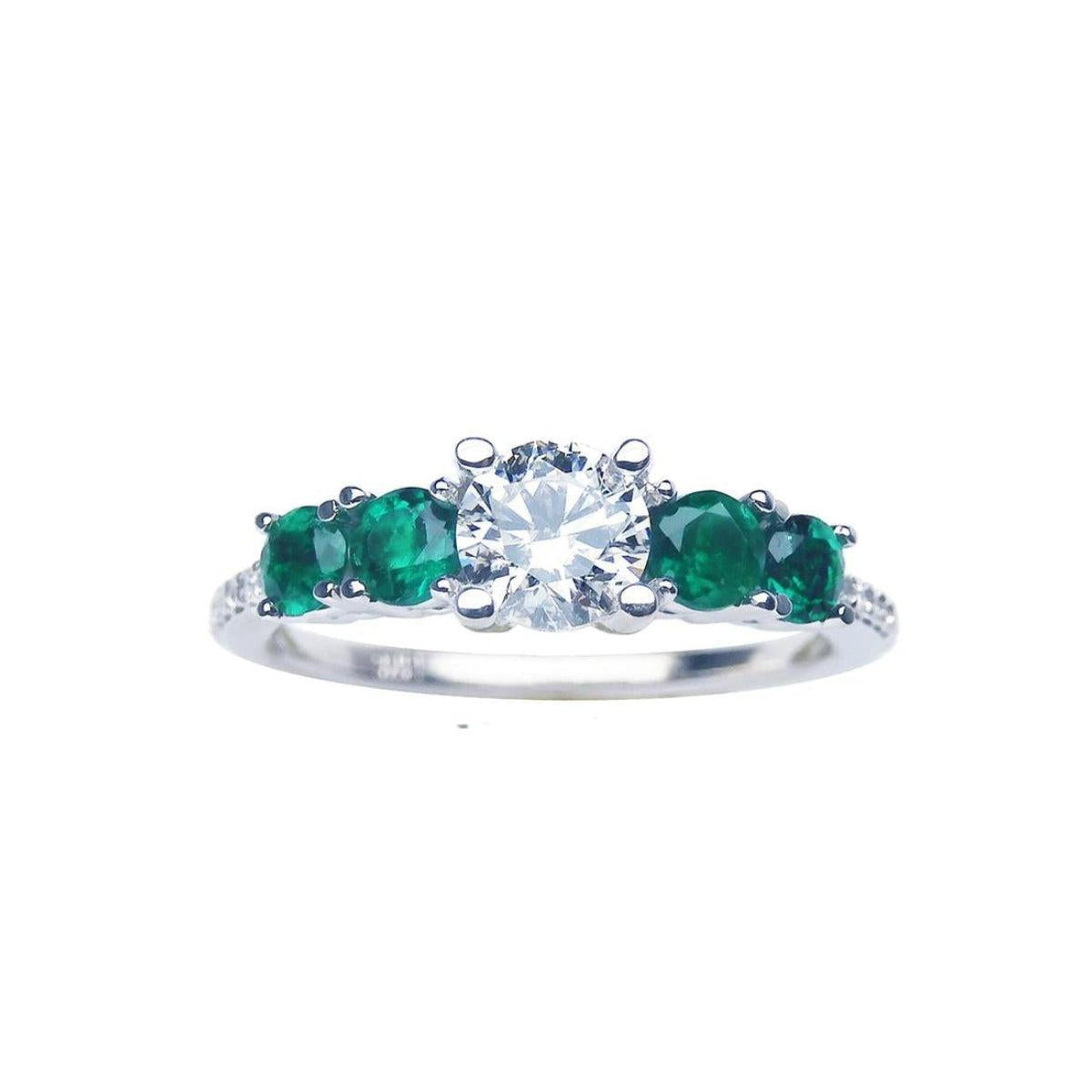 This image shows a ring with a center round cut diamond and side emeralds, displaying the topside profile.