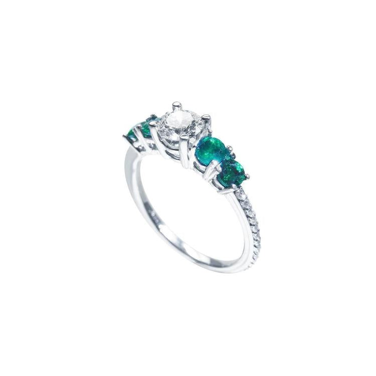14K white gold ring with a round diamond center and four side emeralds.