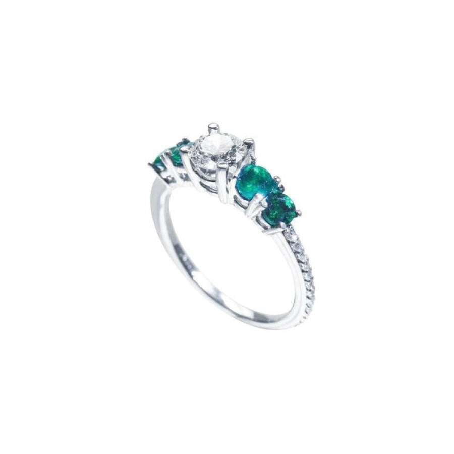 14K white gold ring with a round diamond center and four side emeralds.