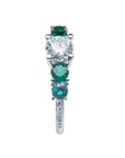 This natural diamond and emeralds ring placed on a side profile view.