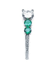 A round cut diamond on top and side emeralds ring profile.