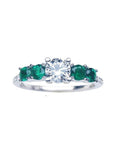 A women's round cut natural diamond ring with side colombian emeralds crafted in 14k white gold.