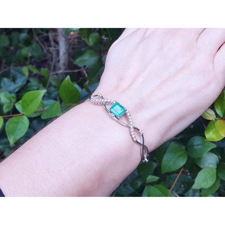 Emerald bangle bracelet with natural diamonds in 14K white gold, worn on a wrist.