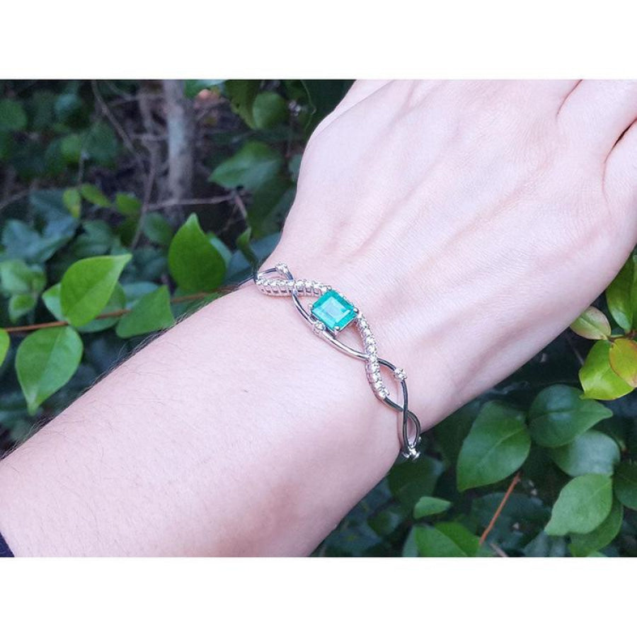 Emerald bangle bracelet with natural diamonds in 14K white gold, worn on a wrist.
