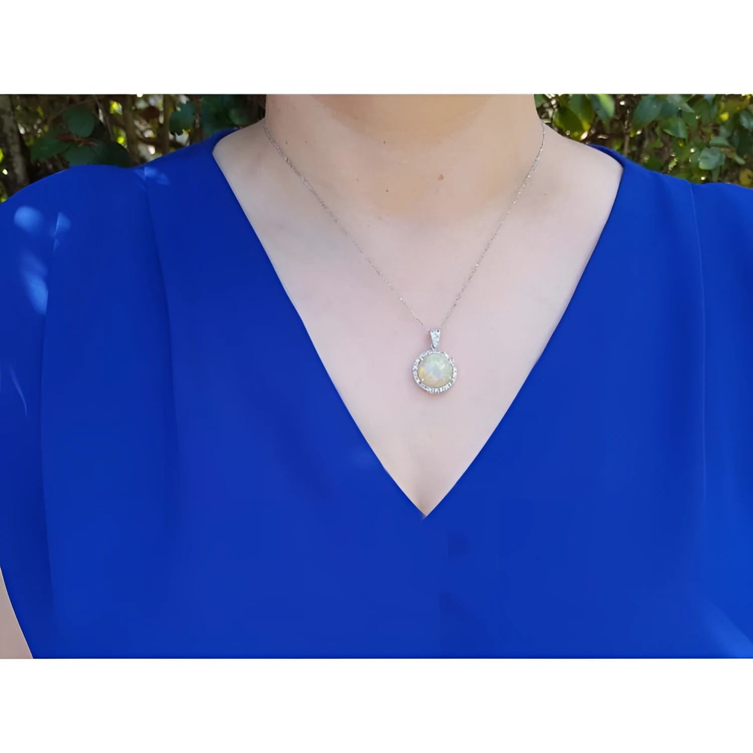 Ethiopian Welo opal and diamond pendant in 14K white gold, worn on a woman's neck.