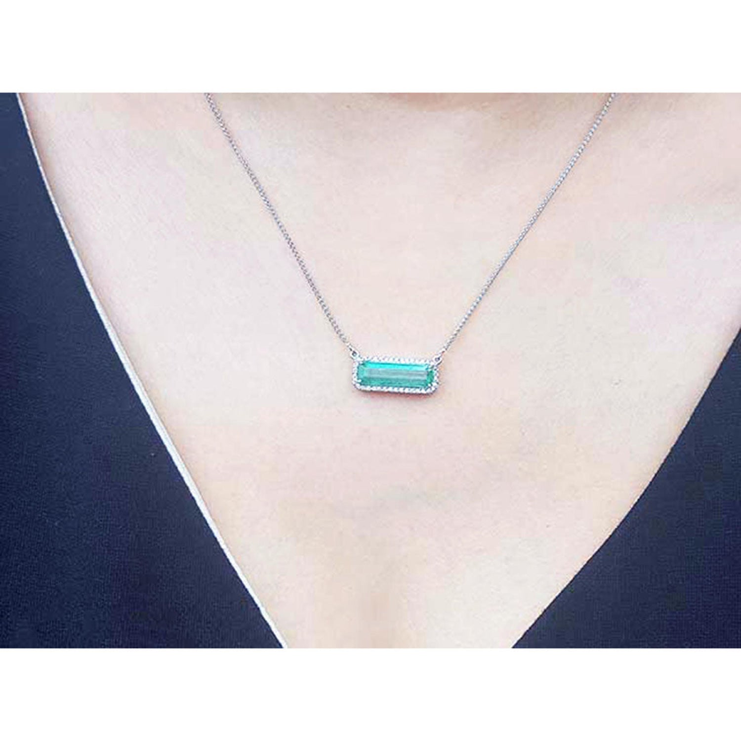 18K white gold necklace with a rectangular emerald-cut Colombian emerald and halo diamonds.