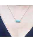 18K white gold necklace with a rectangular emerald-cut Colombian emerald and halo diamonds.