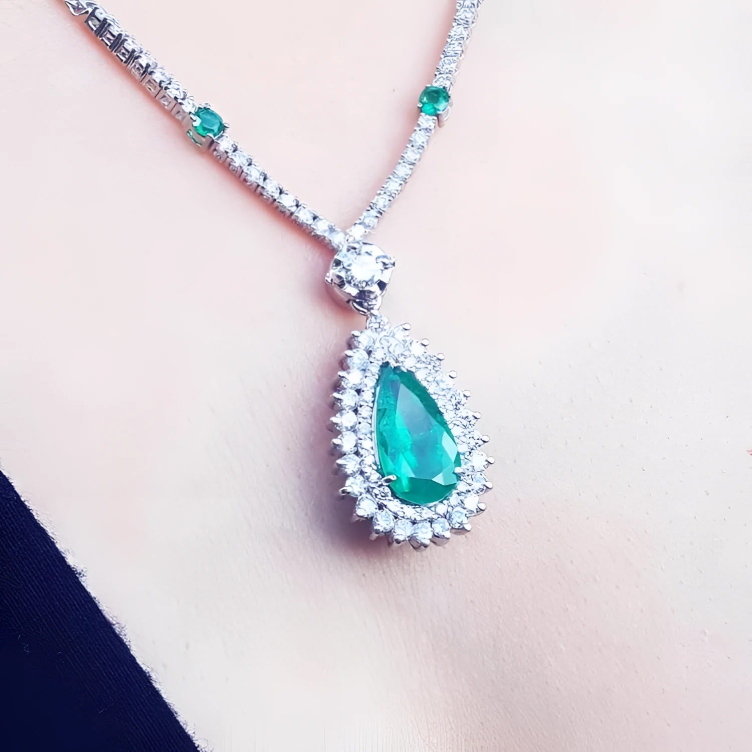 Pear cut emerald necklace with double diamond halo, 18K white gold chain with emerald accents.