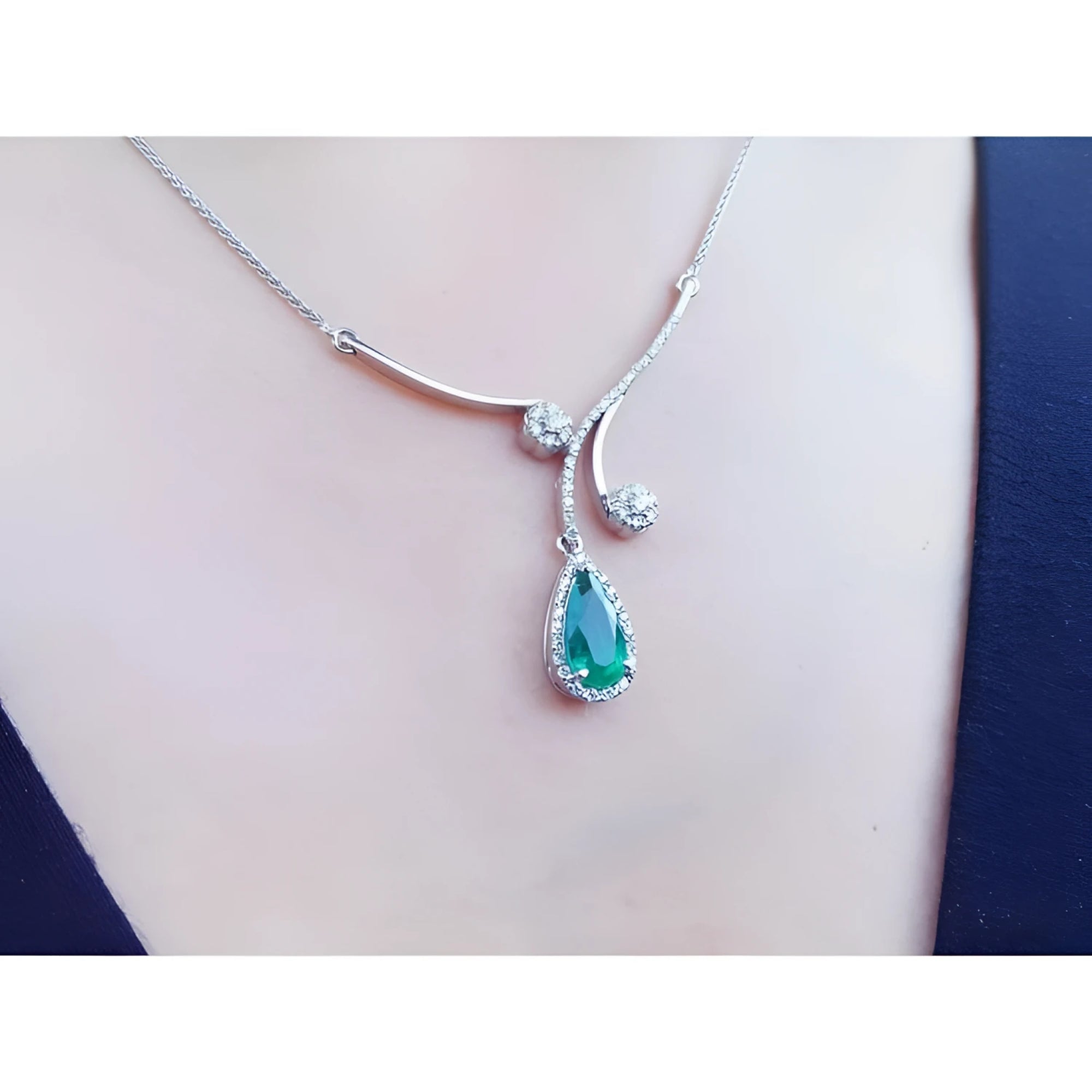 Pear cut deep green emerald necklace with diamond halo and accents, crafted in 18K white gold.