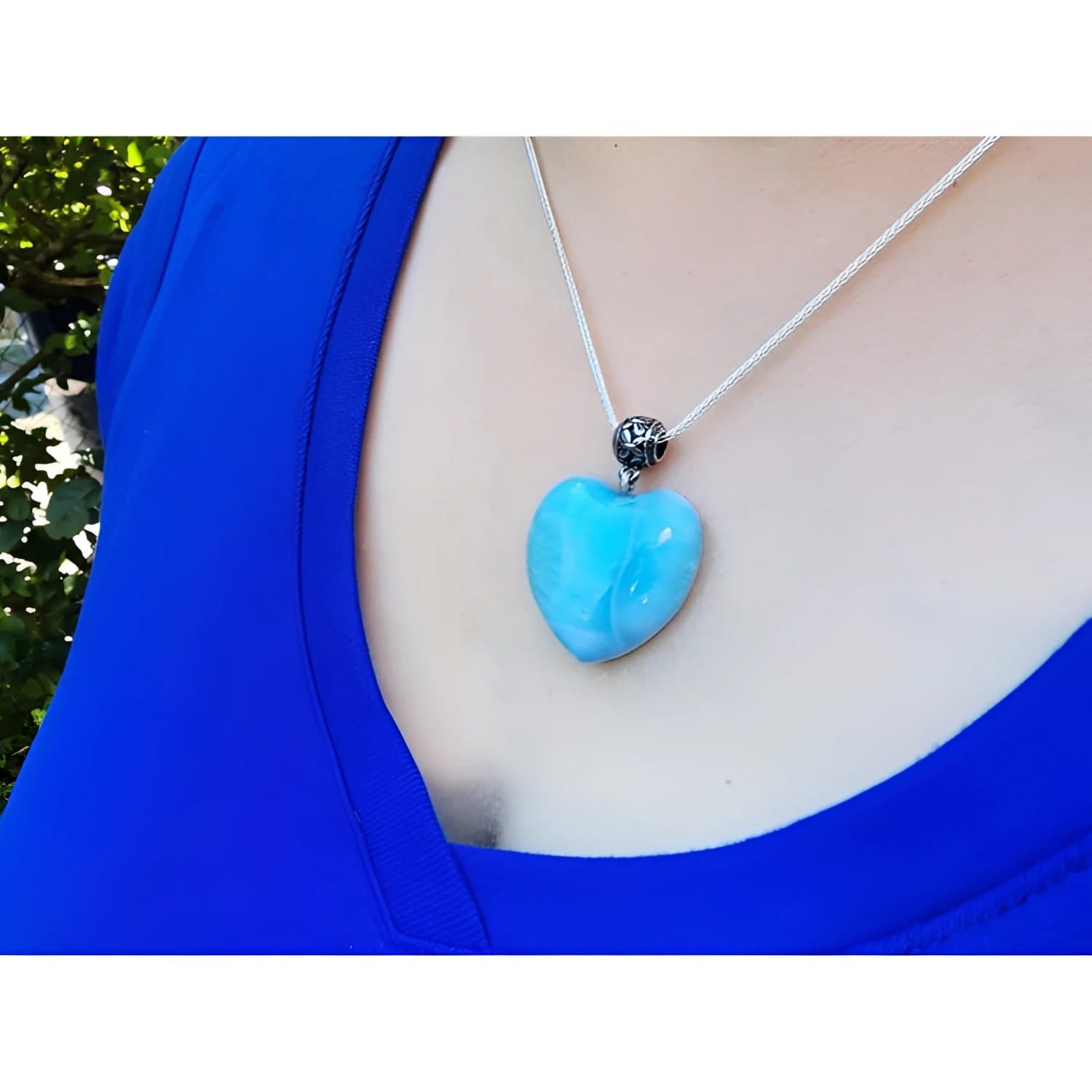 Heart-shaped blue and white Larimar pendant on a sterling silver chain, worn on a person's chest.