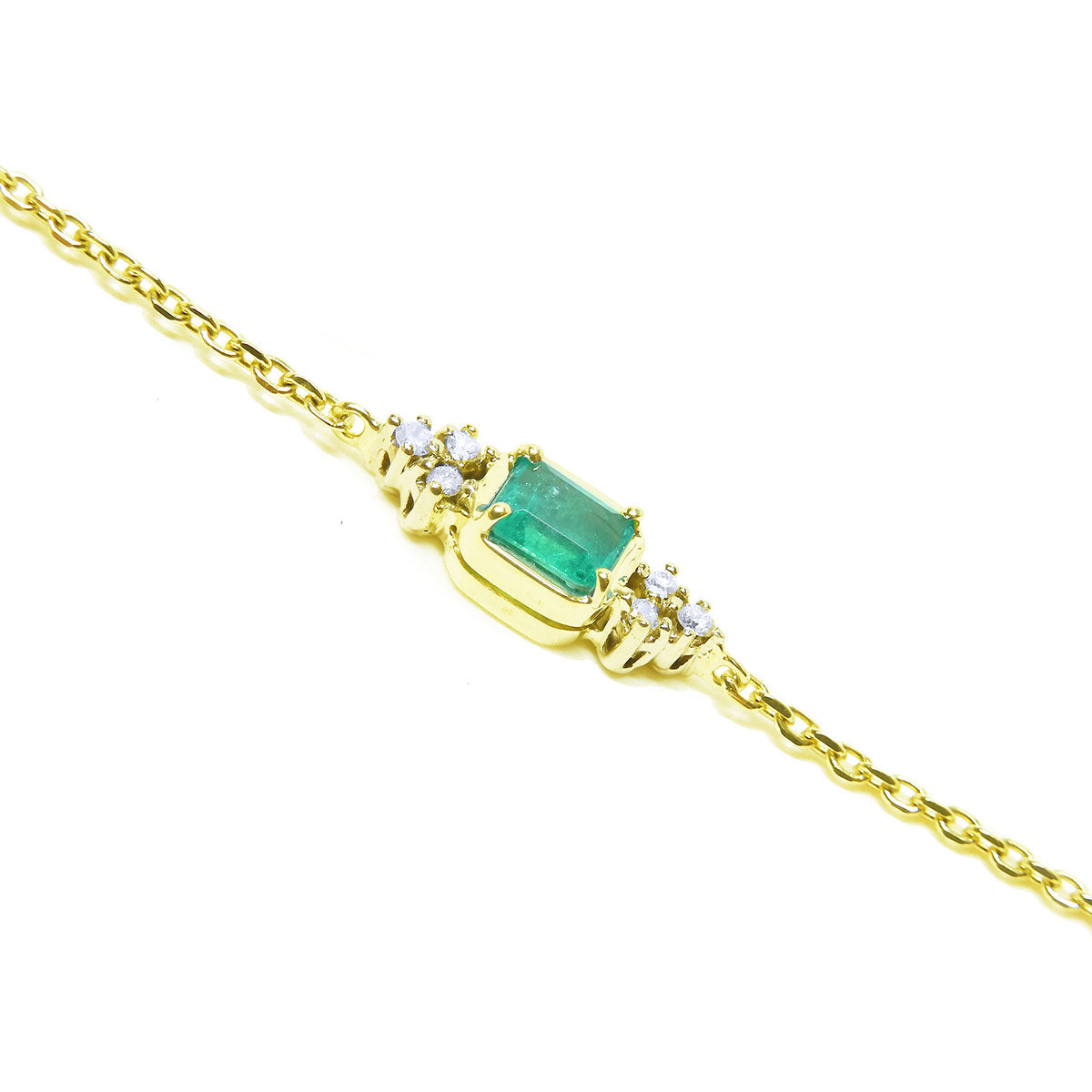 Gold bracelet with a rectangular emerald and small diamonds on a lateral side view.