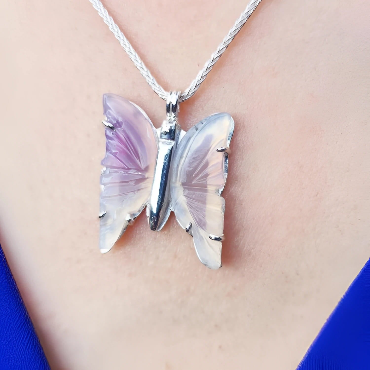 Lavender agate butterfly pendant necklace with sterling silver on a person's chest.