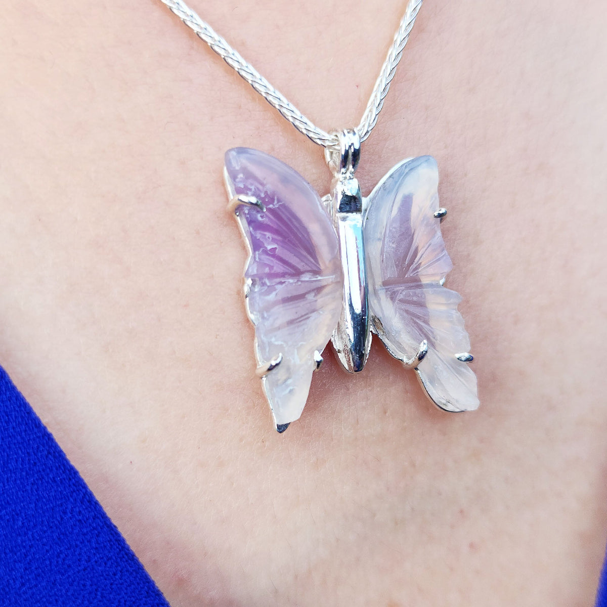 Butterfly-shaped natural agate pendant on a silver chain worn around the neck