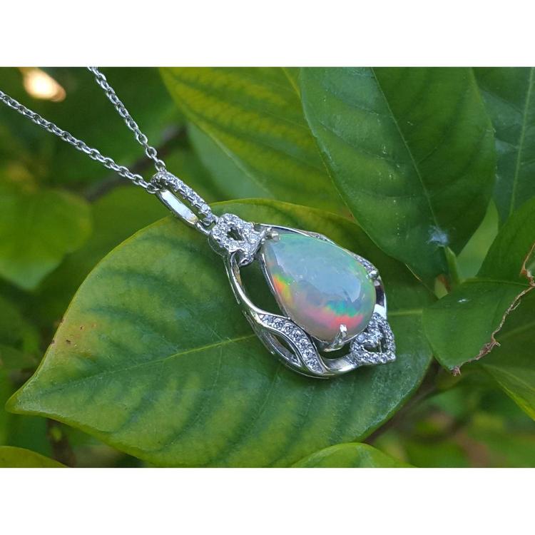 Pear-shaped rainbow Welo Ethiopian opal pendant in sterling silver with cubic zirconia accents on a leaf.